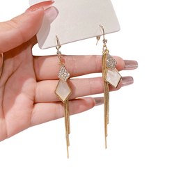 Kullanväriset roikkuvat korvakorut helmiäisvaalealla kuviolla