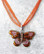 Kimalteleva oranssinruskea emaloitu perhonen kaulakoru