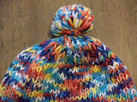 Monivärinen pipo korvaläpillä ja tupsulla, aikuisten koko