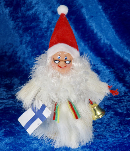 Joulupukki poronkarvapuvussa, kädessä kilikello ja Suomen lippu