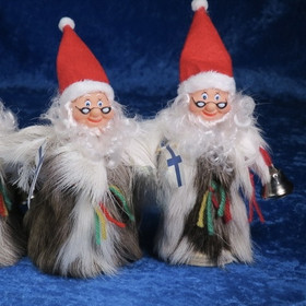 Joulupukki poronkarvapuvussa, kädessä kilikello ja Suomen lippu