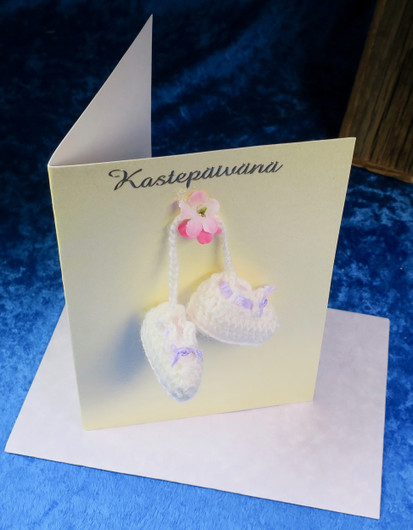 Postikortti Kastepäivänä virkatut vauvatossut ja kukka. KAS1