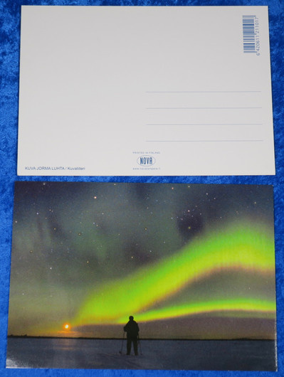 Postikortti revontulet, tähtitaivas ja hiihtäjä kuutamolla