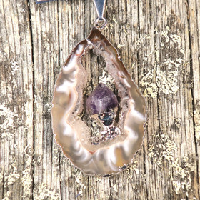 Riipus akaattisiivu, jonka keskellä ametistikide nro AKAM58