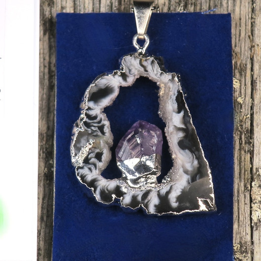 Riipus akaattisiivu, jonka keskellä ametistikide nro AKAM49