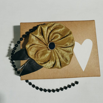 Pinni, vihertävä kukinto mustalla helminauhalla 