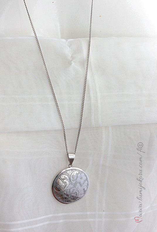 Hopeinen pyöreä riipus pitkässä ketjussa