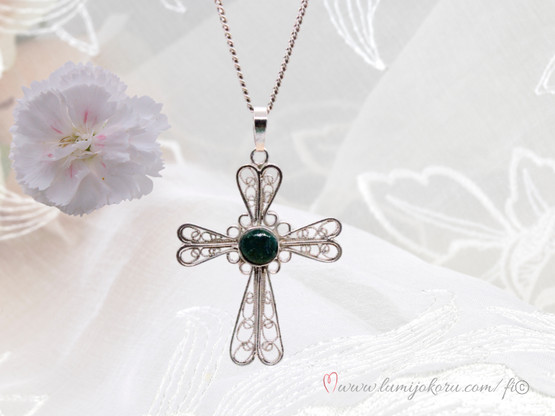 Hopeinen ristiriipus vihreällä kivellä